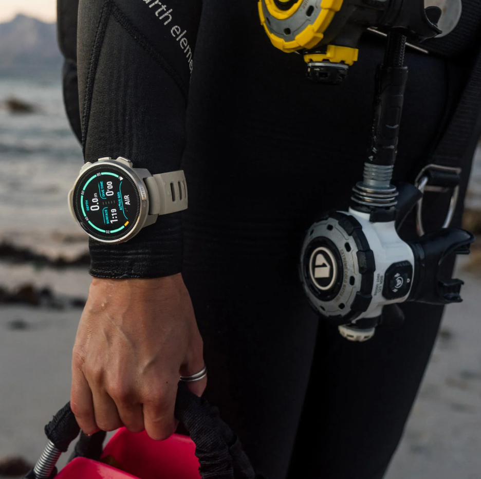 Person in diving gear with a watch on a beach